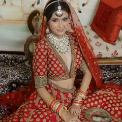 Seated in a regal pose, this bride embodies traditional grace. Her makeup is kept classic with a defined eye and a flawless base, ensuring she looks perfect from every angle.