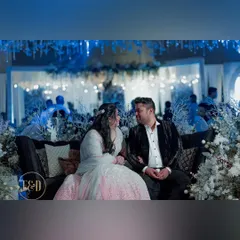 The couple seated amidst the 'enchanted winter' decor. The space is filled with white, frosted branches and cool blue lighting, creating a romantic and ethereal setting.