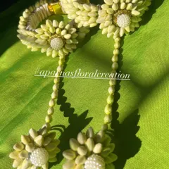 A pair of floral bangles or 'gajra' for the wrist. These are made from tightly woven flower buds and decorated with a floral motif and pearl center.
