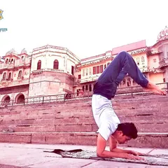 Performing a variation of Vrischikasana, the Scorpion Pose, against the backdrop of Udaipur's Gangaur Ghat. This inversion requires significant strength and control, helping to overcome fear and develop a peaceful, joyful, and exuberant state of being.