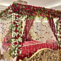 This is a truly grand romantic gesture. The bed is decorated with a stunning arrangement of fresh red and white flowers, with delicate floral strings and petals hanging down for a luxurious wedding night feel.