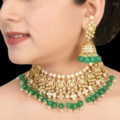 This beautiful Kundan choker with green beads and matching oversized jhumkas is a popular choice for Mehendi or Sangeet ceremonies. The intricate details add a touch of chic sophistication.