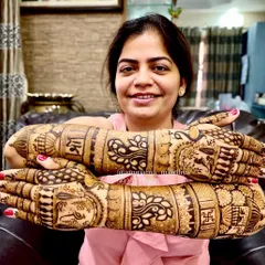 A happy bride flaunting her beautiful backhand henna. This design features traditional motifs like the kalash and tree of life, creating an elegant and meaningful pattern.
