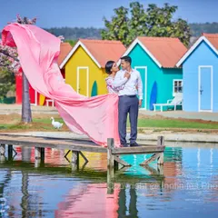 A vibrant shot featuring a flowing pink gown from our collection, set against the colorful boathouses and calm waters of our lakeside location.