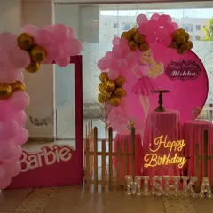 A chic Barbie-themed party in pink and gold. This setup includes a custom backdrop, marquee letters, a neon sign, and a life-size Barbie photo box prop.