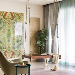 A traditional solid wood swing becomes a stunning focal point against a custom-made tile installation with a bold green marble pattern. This space is designed for relaxation, with an elegant armchair and soft rug creating a perfect corner to unwind.