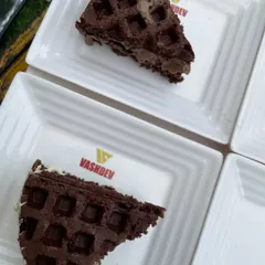 A slice of our decadent chocolate waffle, served on a custom Vashdev plate. We pay attention to every detail, including our branding and presentation.