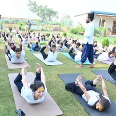 An outdoor class practicing Dhanurasana (Bow Pose) together on the grass. The fresh air and natural surroundings enhance the benefits of the practice.