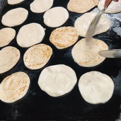 Fresh parathas being cooked on a large tawa. We make our breads live on-site whenever possible to ensure they are served soft and hot, perfect for pairing with our curries.