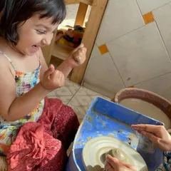 The excitement is real. This little girl is thrilled as she gets her hands messy and shapes the clay, discovering a new way to express her creativity.