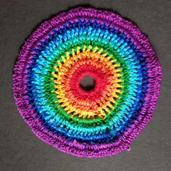 A 6-inch rainbow crochet doily. This can be used as a coaster, a base for a small vase, or as part of a dreamcatcher.