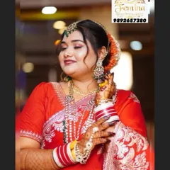 A happy bride in a classic red saree. The makeup is soft and glowing, with defined eyes and a smile that says it all. The hair is styled in a traditional bun with orange flowers.