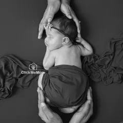 This portrait shows a newborn held securely in her parents' hands. The black and white format emphasizes the feeling of safety, love, and protection.