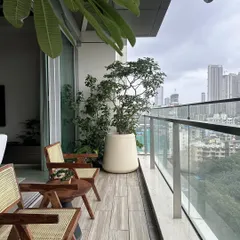 Another view of the Lumen House balcony, where the custom wooden chairs with woven details add warmth and texture. Paired with oversized planters, the space becomes a vibrant, green escape from the city.