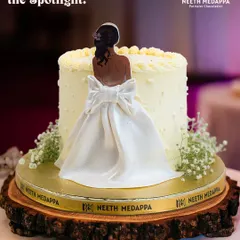 A cake that steals the spotlight. This elegant creation features a beautiful, handcrafted sugar figure of a bride in her wedding dress, making it a stunning and personalized centerpiece for a bridal shower or engagement party.