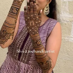 A stylish design featuring a prominent jaali pattern on the back of the hand, personalized with the initial 'R'. The forearm continues the theme with classic peacock art.