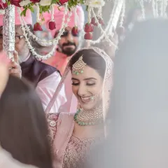 The bride's emotional and joyful entry, surrounded by her family under a canopy of flowers. This candid shot captures the mix of happiness and anticipation that defines the bridal procession.