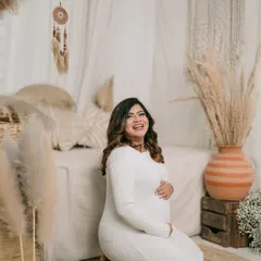 A joyful, candid shot of the expectant mother. Her radiant laugh and the way she cradles her bump perfectly capture the happiness of this special time.