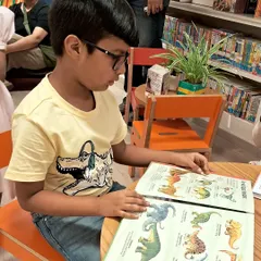 This young reader is exploring a book about dinosaurs. We offer a wide variety of non-fiction books that cater to the specific interests and curiosities of every child.