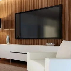 A perfect example of a modern media wall that blends seamlessly into the living room decor. The television is mounted on a rich, fluted wood panel, complemented by a minimalist white console that keeps the space feeling clean and uncluttered.
