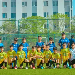A youth team poses for a group photo with their coach, proud and united after a successful tournament.