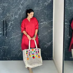 This pose shows the tote from a different angle, highlighting the textured fabric and the craftsmanship of the handcrafted embellishments.