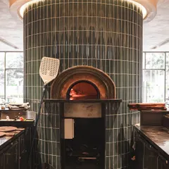 The centerpiece of our Bellandur location: a stunning, green-tiled, cylindrical brick oven that's both a functional kitchen and a design statement. It's a vibe.