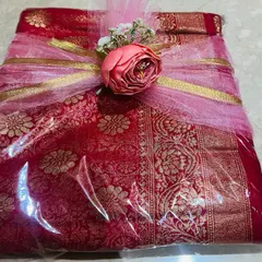 I love creating a soft and dreamy look for your gifts. This classic red and gold saree is wrapped in delicate pink tulle and tied with a matching flower, giving it a romantic feel that’s perfect for an engagement or wedding gift.