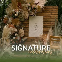 A signature boho-chic setup against a rustic wooden wall. The arrangement of dried pampas grass, palm leaves, and fresh flowers creates a stunning, textural backdrop.