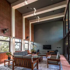 Inside The Grey Grotto, a double-height living area combines exposed brick walls and expansive glass panels. This space is designed to feel both grand and inviting, blurring the line between the interior and the lush exterior.