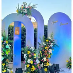 For a more modern look, I designed this wedding backdrop using custom arches and asymmetrical floral arrangements. The blue uplighting gives it a unique and stylish feel for evening events.
