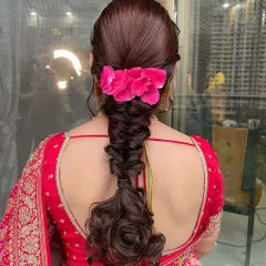 A stunning braided hairstyle for this client. The intricate braid is adorned with bright pink flowers, adding a beautiful pop of color to her traditional look.