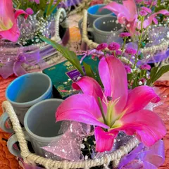 A close-up of the floral hampers created for a corporate event. The combination of fresh lilies, premium tea, and ceramic mugs makes for a sophisticated and thoughtful gesture.