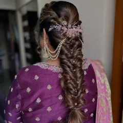 I believe a bride's hairstyle should be a work of art. This intricate fishtail braid, woven with delicate pearl chains and crowned with a floral accessory, is a perfect example of the romantic and detailed hair artistry I provide.