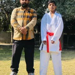A student stands proudly with Sensei Amresh Singh after his belt test. Earning a new belt is a significant milestone in a karateka's journey.