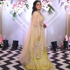 Here is a full view of the pastel yellow lehenga, showing the flow of the skirt and the delicate embroidery on the sheer dupatta. It's both elegant and easy to wear.