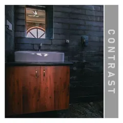 A bathroom detail showing the beautiful contrast between the dark, rough texture of slate stone walls and the smooth, warm finish of the wooden vanity.