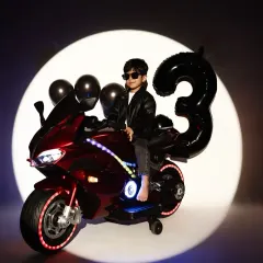 Celebrating a third birthday with style. This fun, biker-themed studio shoot features dramatic lighting and cool props like a toy motorcycle, perfect for capturing your child's personality.