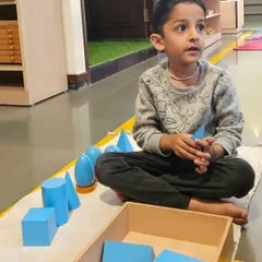 Exploring geometric solids helps children understand three dimensional shapes in their environment. This sensorial work allows them to distinguish different forms like cubes, spheres, and cones by touch and sight, building a vocabulary for the world around them.
