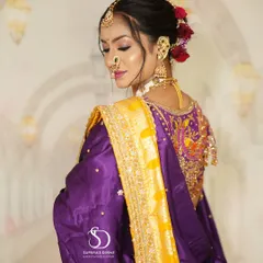 The elegance of a Marathi bride captured from the side. This angle highlights the intricate bridal bun, adorned with fresh red roses, and the detailed embroidery on the blouse.