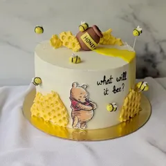 What will it bee? A sweet surprise is on the way with this Winnie the Pooh gender reveal cake. The design features Pooh bear, a honey pot, and buzzing bees.