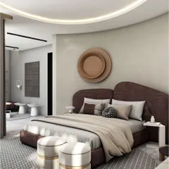 In the SR Residence villa, this bedroom features a sculptural curved fabric headboard that wraps around the bed. The design uses a harmonious blend of beige and grey tones, enhanced by a statement circular ceiling detail with integrated lighting.
