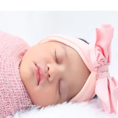 The perfect pout of a sleeping baby girl. This detailed shot highlights her rosy cheeks and the sweet pink bow on her head.