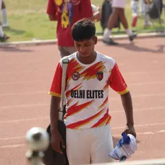 A player walking off the pitch after a hard-fought match, carrying his gear and the day's experience.