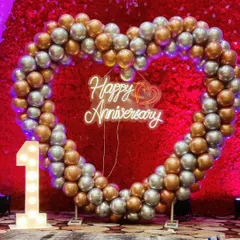 A perfect photo booth for a first anniversary celebration. This large heart-shaped arch is made of silver and gold chrome balloons, with a 'Happy Anniversary' neon sign and a light-up number '1' to mark the special milestone.