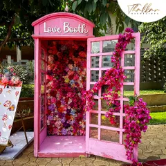 A 'Love Booth' in the style of a classic pink telephone box, filled with flowers. This served as a unique and incredibly popular photo booth at an outdoor wedding.