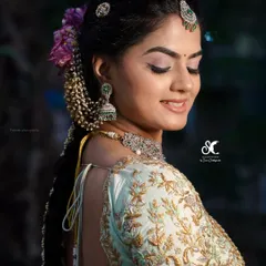 A side view of an elegant bridal hairstyle. The hair is braided and adorned with a pearl accessory, with soft tendrils framing the face for a romantic touch.