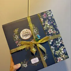 A beautifully wrapped birthday gift box with elegant floral paper and a gold ribbon. The first impression of a gift should always be special.
