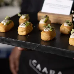 A server presenting a tray of our bite-sized appetizers at an event. These mini-quiches are filled with creamy toppings and fresh herbs, showcasing our commitment to quality and presentation in our pass-around service.