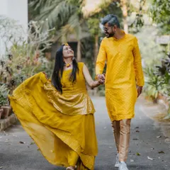 A beautiful shot of the couple walking hand-in-hand after their Haldi ceremony. Their coordinated yellow outfits and happy smiles radiate warmth and love.